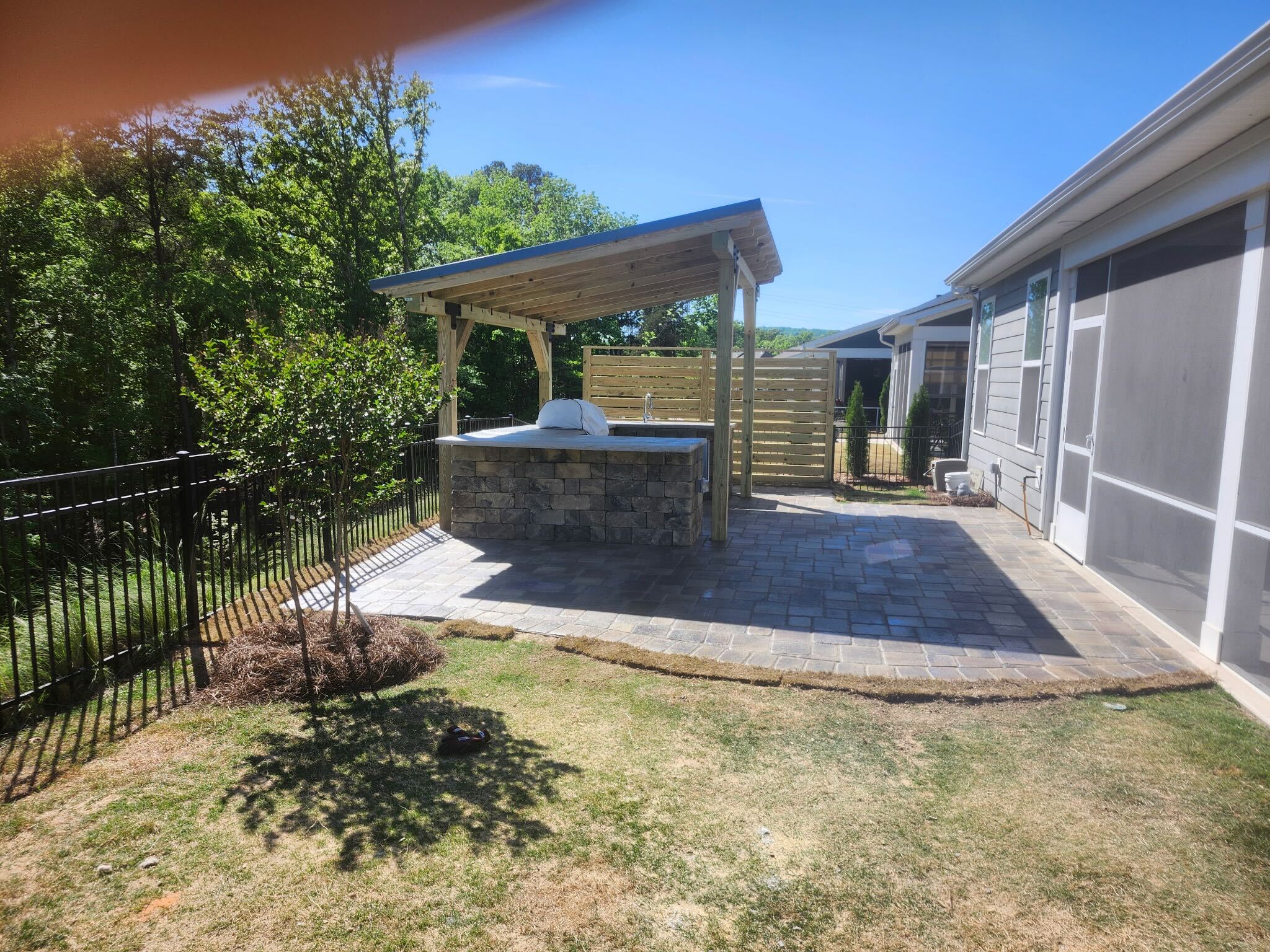 Paver patio and outdoor kitchen against a private backyard